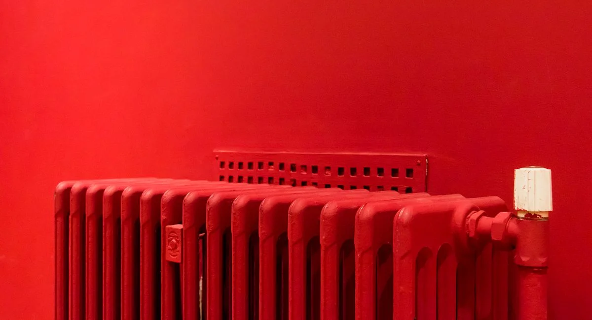 A vibrant red radiator against a matching wall captures minimalist and modern interior design.