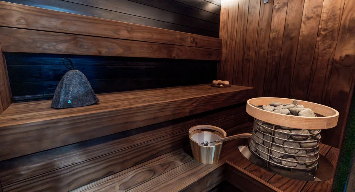 Luxurious indoor sauna featuring dark wood, LED lights, and a HUUM electric heater.