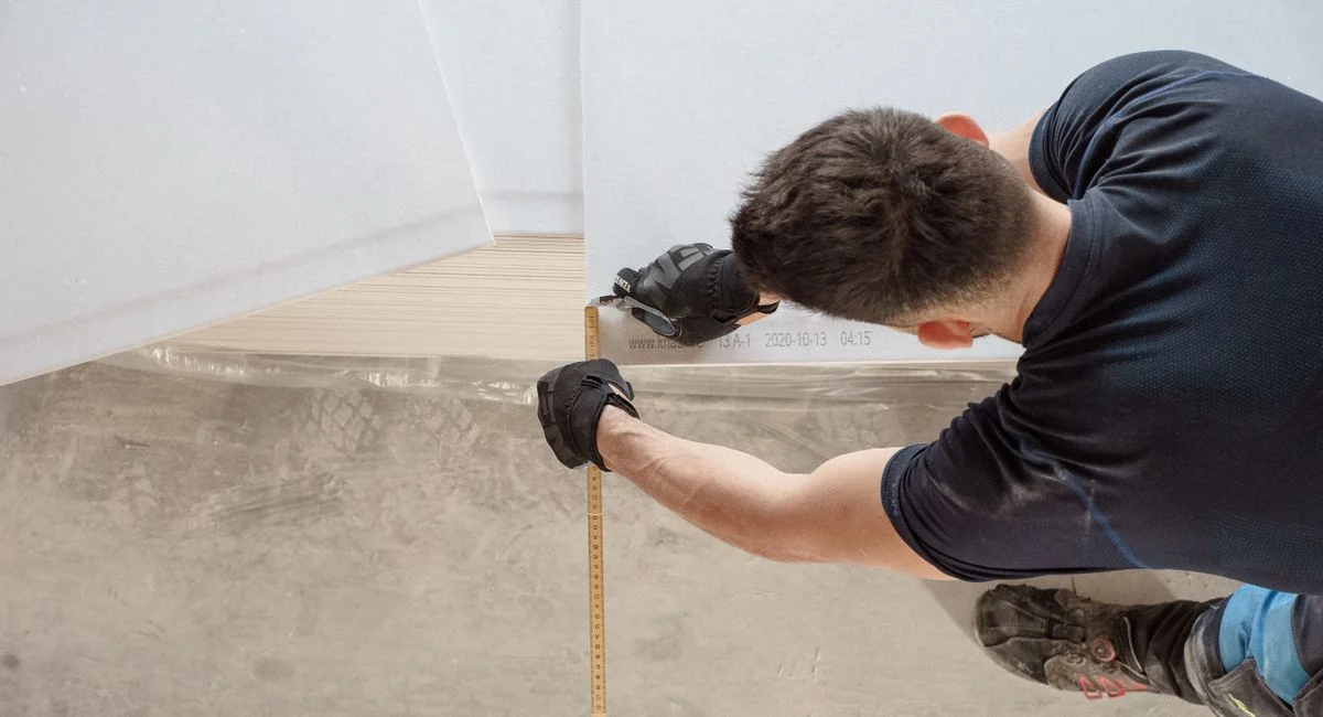 Construction worker measuring and cutting flooring panels in a renovation project.
