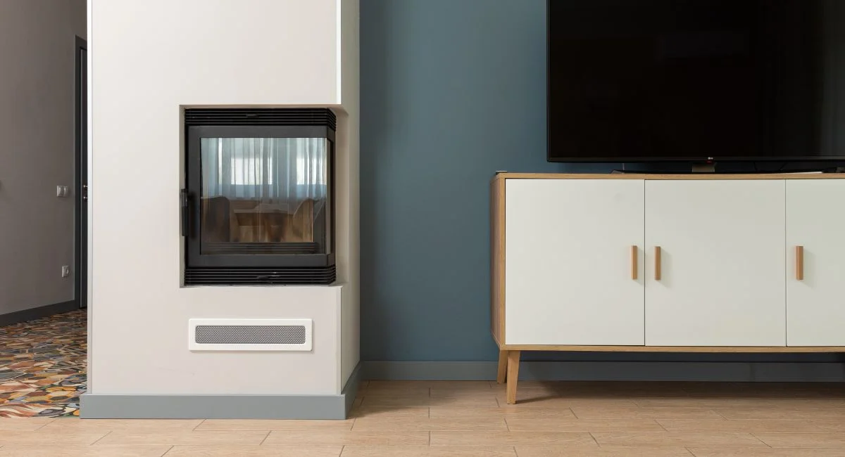 Modern design of contemporary apartment with big TV set placed on white stand near fireplace mounted in construction box
