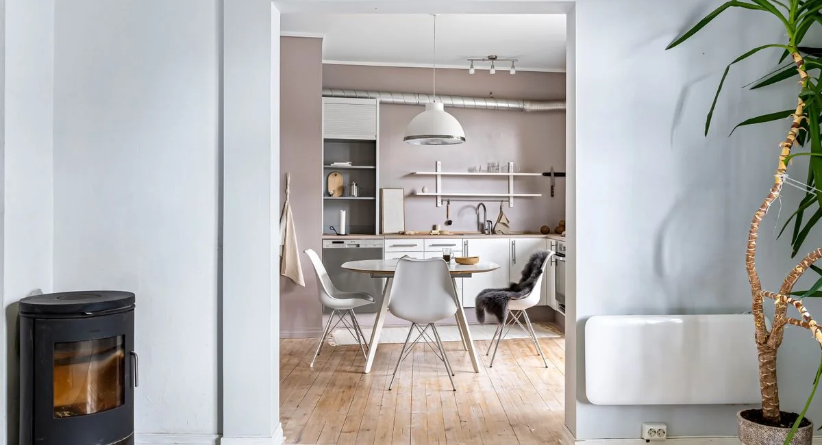 Bright open kitchen featuring modern Scandinavian design with fireplace and wood flooring.