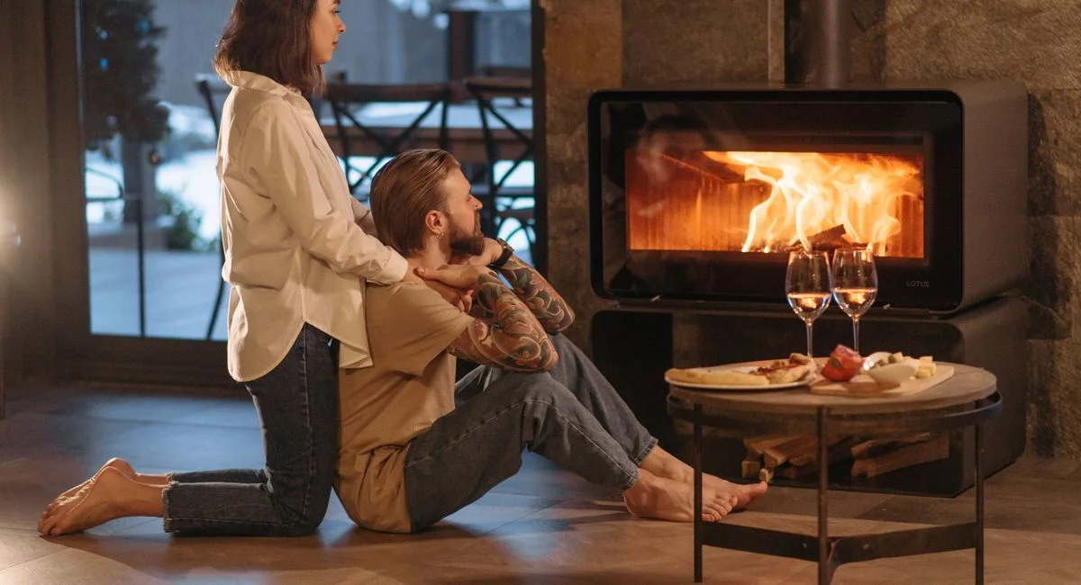 A couple relaxing by a warm fire with wine and snacks, creating a cozy winter mood.