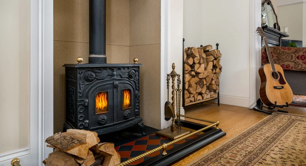 Inviting interior featuring a warm fireplace, stacked wood, and a guitar for a cozy ambiance.