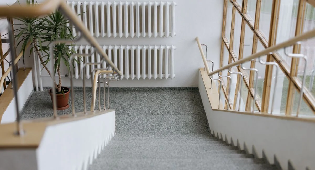 A sleek indoor stairway with modern railings and large windows, offering a minimalist design.