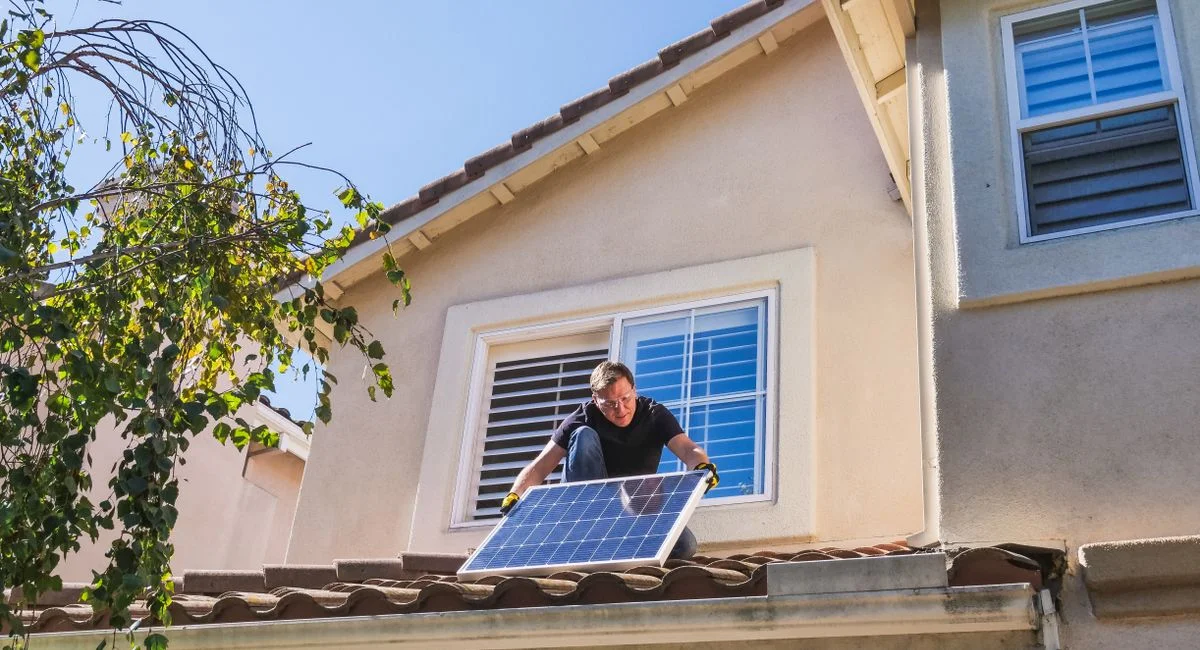 Solar technician installing photovoltaic panels on a sunny rooftop.