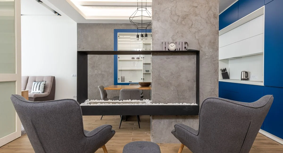 Modern design of studio apartment with comfortable armchairs placed near fireplace in kitchen with minimalist interior