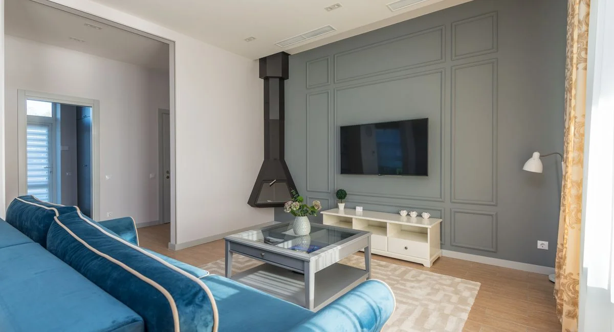 A stylish living room featuring a blue couch, wall-mounted TV, and elegant decor.
