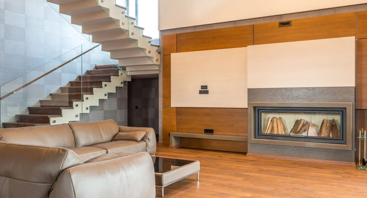 Modern living room featuring a minimalist design with a sleek staircase and comfortable leather sofa.