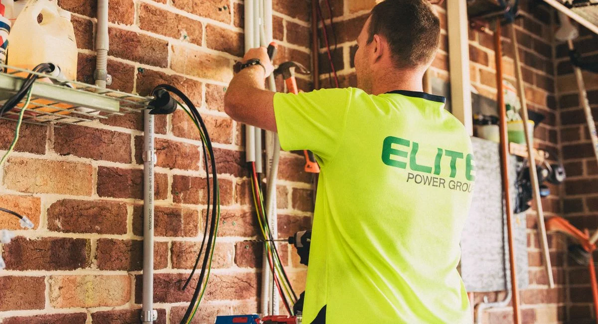 Electrician performing solar battery installation for sustainable energy storage in a home setting.