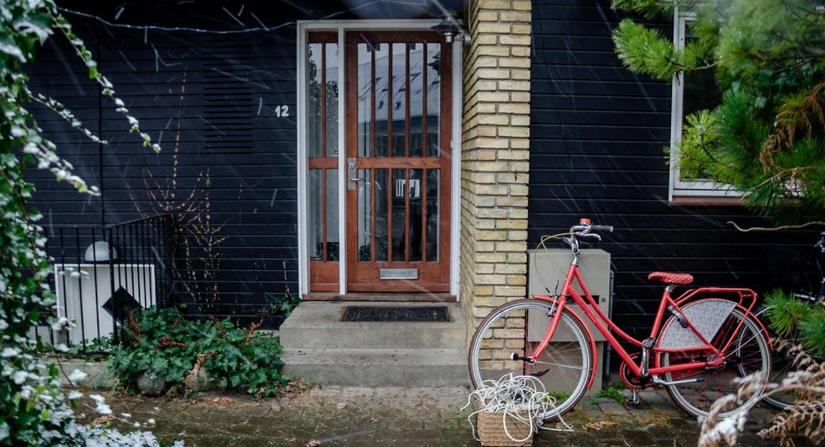 Red bicycle parked in front of a house entrance in Copenhagen, Denmark.