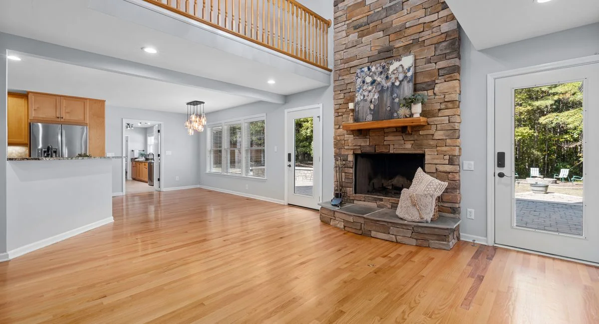 Bright and spacious living room showcasing a modern stone fireplace and high ceilings.