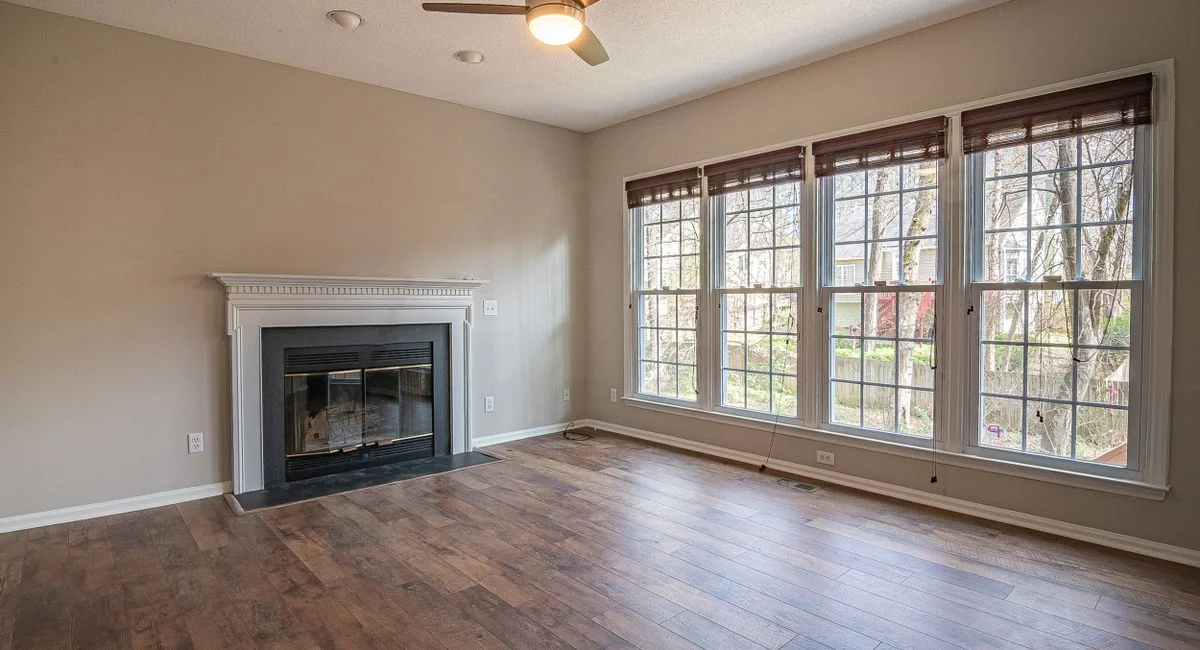 A bright and spacious modern living room interior with a fireplace and large windows.