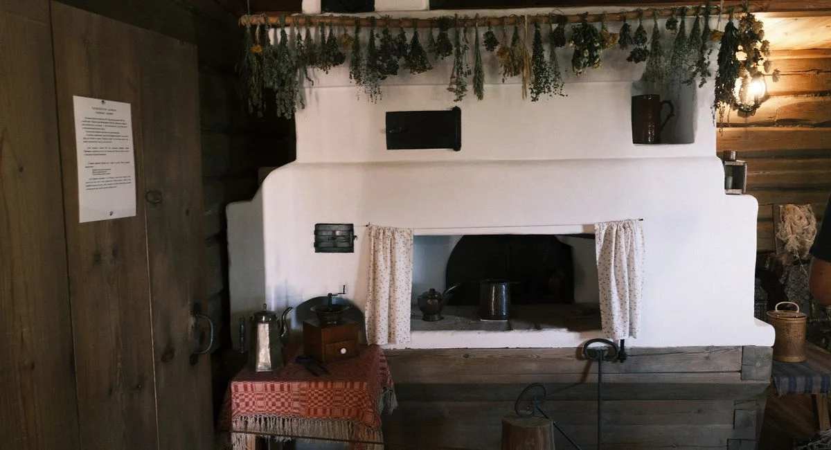 Cozy rustic room with traditional fireplace, hanging herbs, and wooden furnishings, capturing a vintage homely feel.