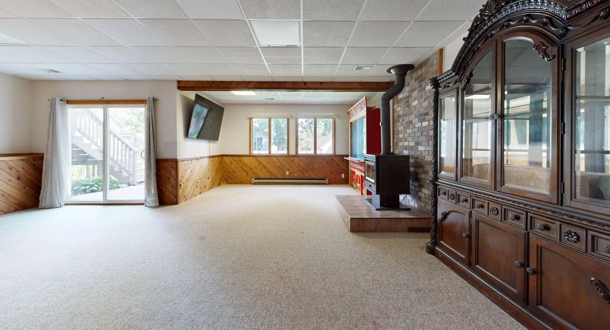 Cozy basement with wooden paneling, fireplace, and sunny windows. Great for relaxation.