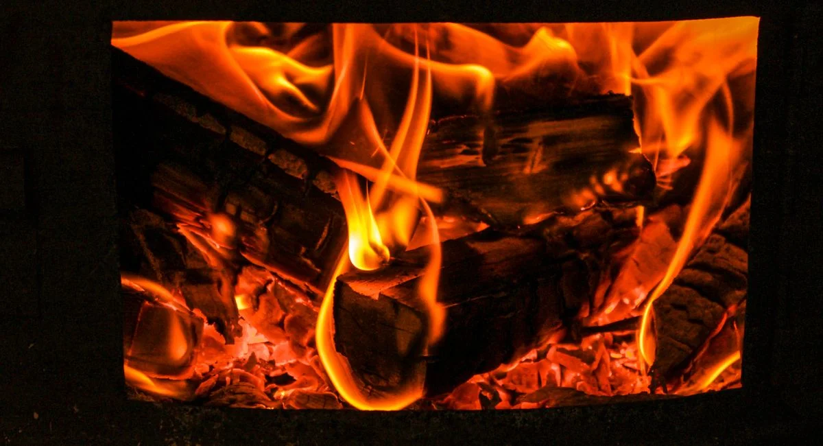 Close macro shot of vibrant orange flames engulfing firewood in a stove.