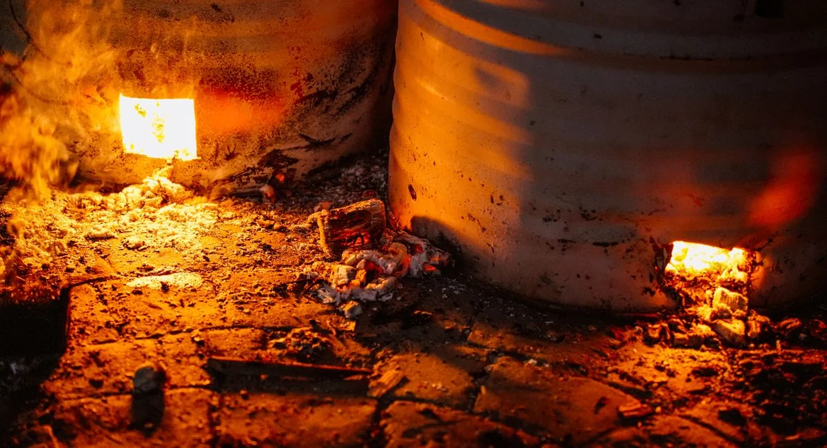 Close-up of glowing embers inside metal barrels emitting warm light.