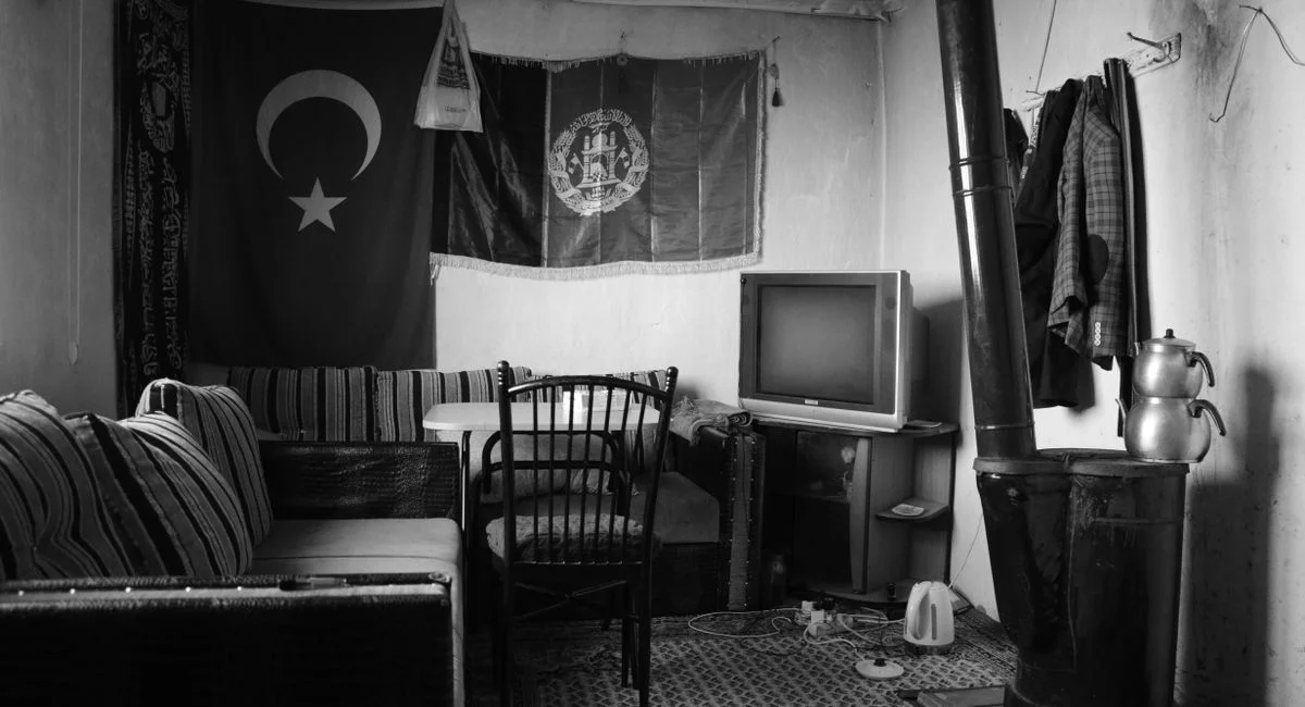 A vintage styled room featuring a Turkish flag, comfortable seating, and a traditional stove.