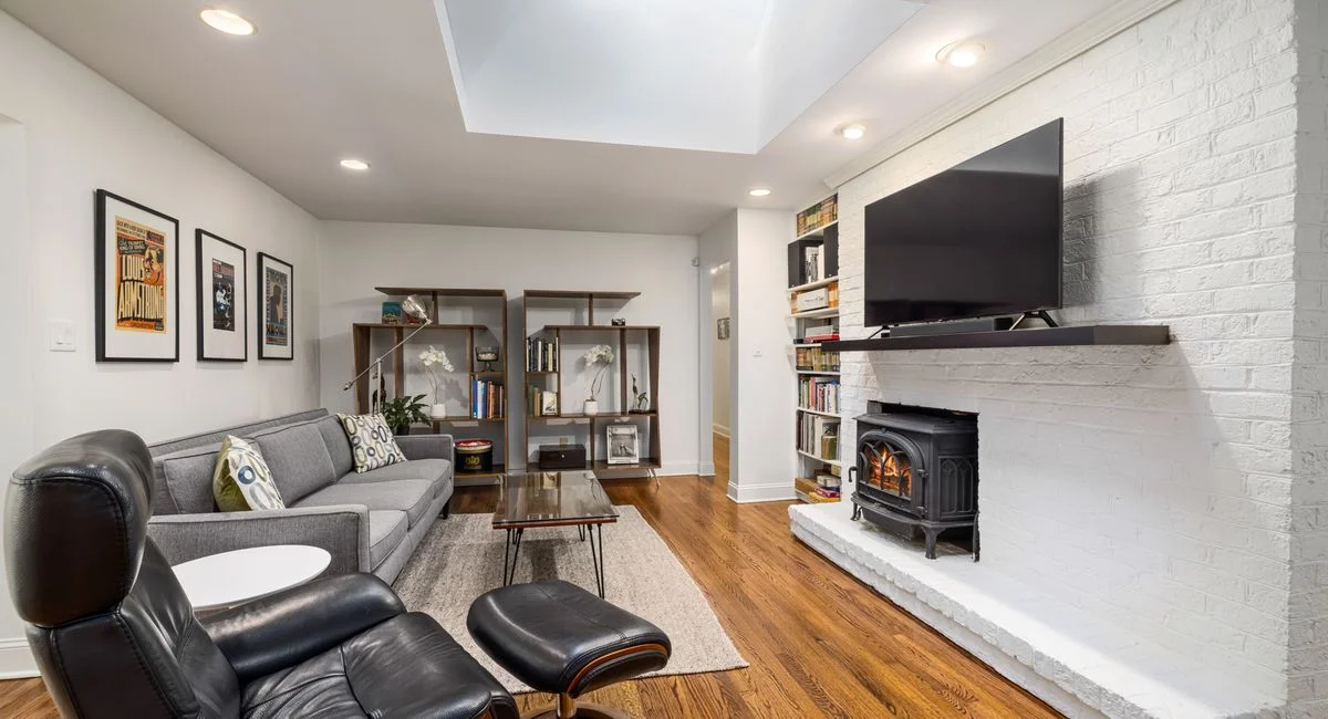 Stylish living room interior featuring a modern design with a skylight, fireplace, and comfortable seating.