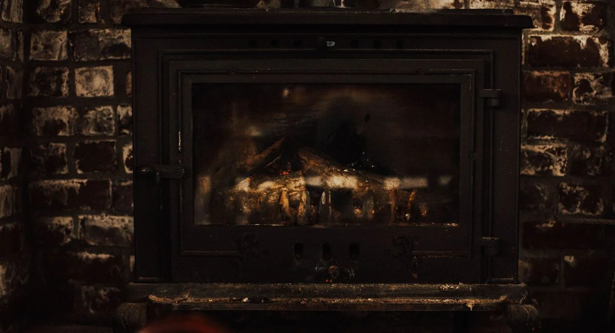 A warm and inviting vintage fireplace against a rustic brick wall, perfect for cozy winter settings.