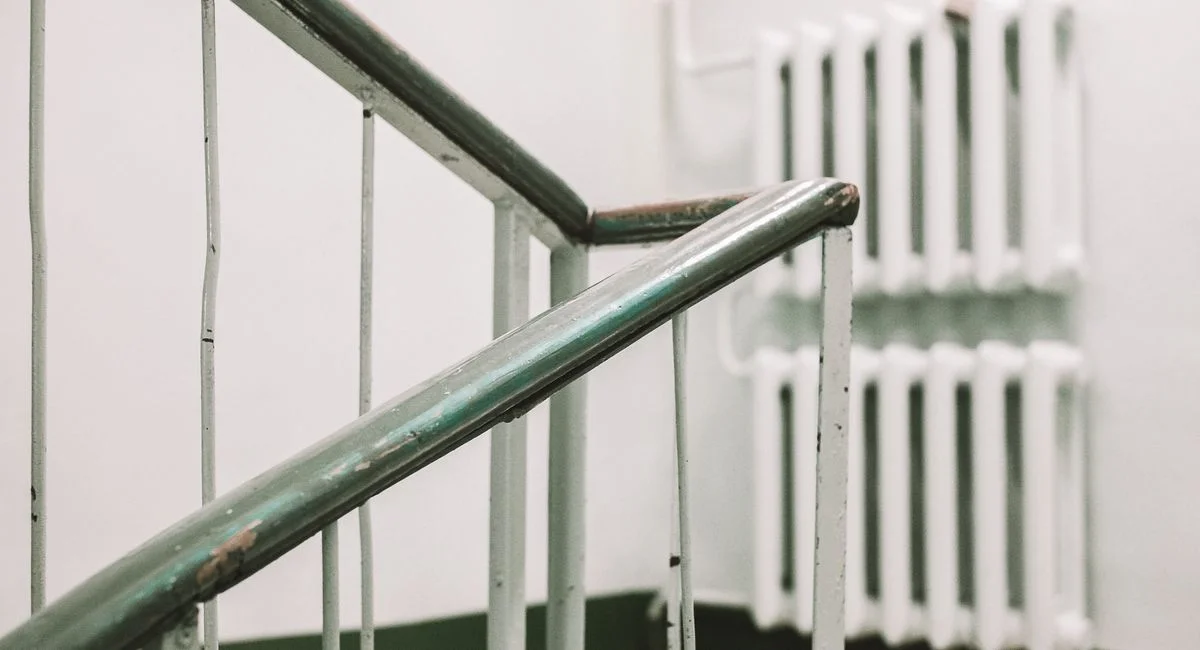 A close-up view of a worn metal handrail and radiator indoors, captured with artistic flair.