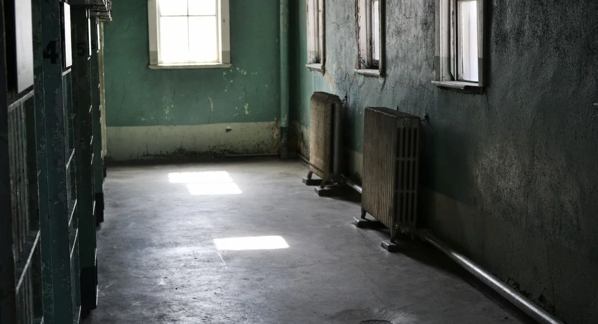 An empty hallway in an abandoned building with sunlight streaming through windows.