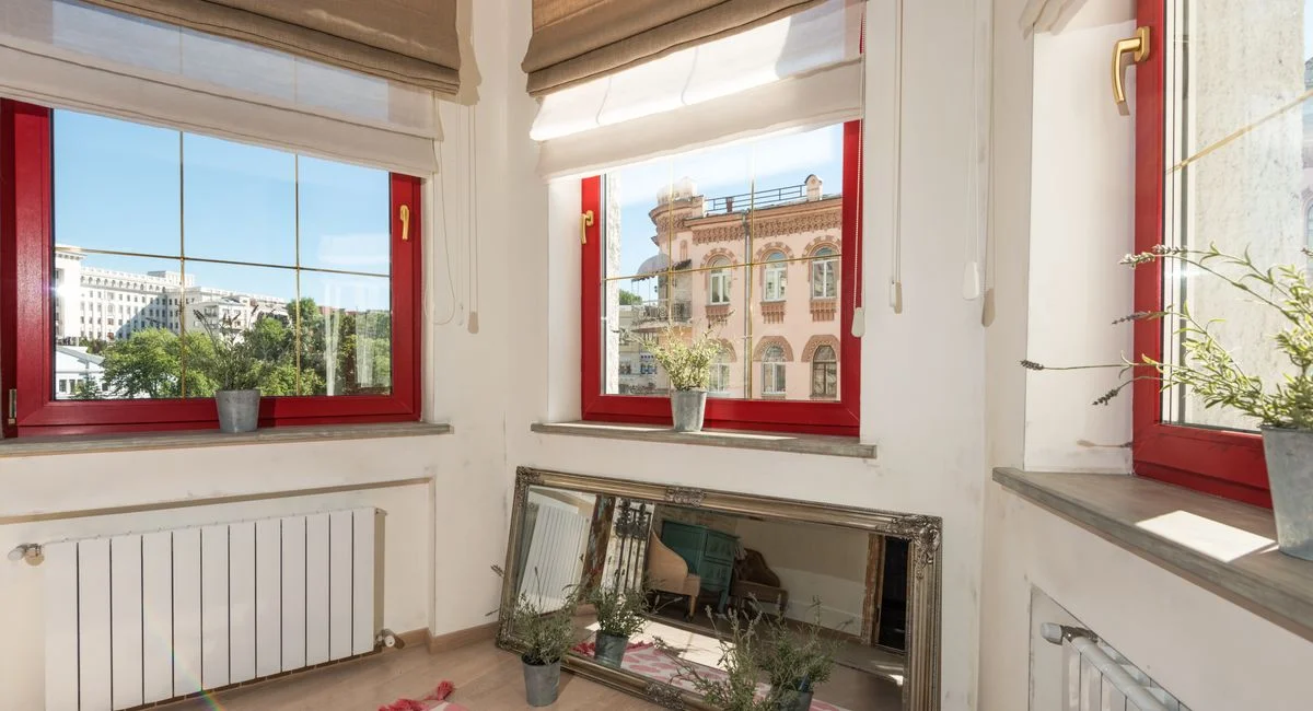 Bright apartment interior showcasing red windows overlooking the city.