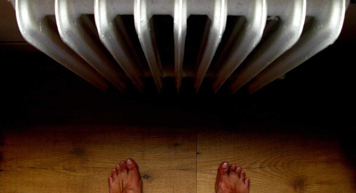 A unique perspective from above showing bare feet standing on wooden floor near a radiator.
