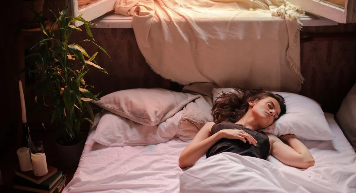 A woman sleeps peacefully in a sunlit bedroom, capturing the essence of a tranquil morning.