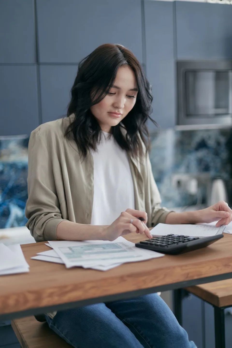 Une personne examine ses factures avec une calculatrice à la maison